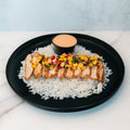 The Southwest Chicken Bowl features sliced grilled chicken with corn salsa over white rice, paired with creamy sauce. This gluten-free, high-protein meal is perfect for meal prep and served on a black plate.