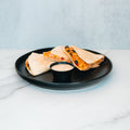 Three wedges of the Southwest Chicken Quesadilla, filled with melted cheese and vegetables, are arranged on a black plate alongside a small cup of chipotle sauce, set atop a white marble surface—perfect for healthy meal prep or enjoying as a flavorful spin on the classic quesadilla.