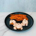 A black plate with three Buffalo Chicken Meatballs topped with creamy sauce and herbs, served alongside sweet potato fries on a light marble surface—a perfect option for healthy dinner meal prep.