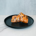 A Broritto Burrito, grilled and cut in half to reveal its filling of chicken, corn, black beans, and vegetables, sits on a black plate atop a white marble surface.