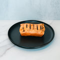 A Broritto Burrito with visible char marks sits on a black plate atop a marble countertop, offering a deliciously smoky and high-protein twist to your meal.