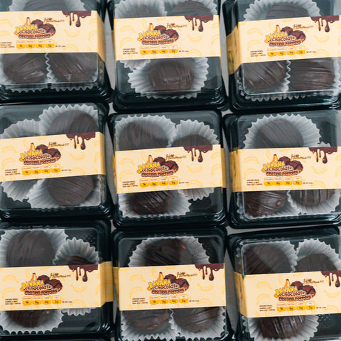 Plastic containers of 3 Banana Chocolate Protein Poppers are arranged in a grid. Each has a beige label with chocolate graphics, and the high-protein treats inside are served in white paper cups for a healthy snack option.