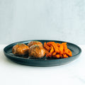 Bourbon Turkey Meatballs served on a dark plate with herbs and sweet potato fries on marble—this macro-friendly, high-protein meal prep option is perfect for healthy eating.