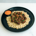 Enjoy “GLORIOUS GAINS” Steak Bites Cilantro Lime Rice—a high-protein meal with tender steak bites on cilantro lime rice, garnished with herbs, and served alongside a zesty orange dipping sauce. Perfect for easy meal prep.