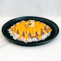 The Cheeseburger Bowl is served on a black plate with white rice, savory ground beef, orange cheese sauce, mashed potatoes, and green relish at the center. It’s gluten-free.