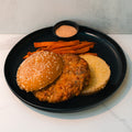 A black plate with the Chicken Veggies Burger, sweet potato fries, and a cup of dipping sauce on a white surface—perfect for a high-protein meal.