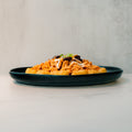 Peak Load Chick'n Tots served on a dark plate, topped with shredded cheese and beans, set on a light marble surface against a pale textured background—a high-protein comfort meal.