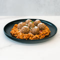Garden Orzo Meatballs features cooked orzo pasta in tomato sauce, eight meatballs, and grated cheese for a delicious high-protein meal prep, served on a black plate over white marble with a light gray background.