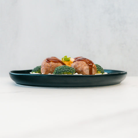 Pineapple Teriyaki Meatballs served with steamed broccoli and mashed potatoes create a delicious, high-protein meal prep, plated on black dishware against a light background.