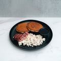 The Snickerdoodle Pancake Breakfast features two snickerdoodle pancakes, scrambled eggs, cooked bacon, and sugar-free syrup on a black plate atop a white marble surface.