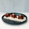 Caribbean Jerk Meatballs glazed in barbecue sauce and herbs are served over high-protein rice, creating a flavorful and meal-prep friendly bowl, beautifully presented on a dark plate against a light background.