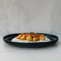 Chicken Tikka Masala: Tender golden-brown chicken in red tomato sauce and herbs over white rice on a black plate, set against a light gray background—a high-protein, gluten-free meal.
