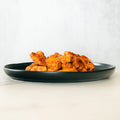A black plate with golden-brown, crispy Competition Approved Chicken Kebab 1lb sits on a light-colored surface against a plain white background.