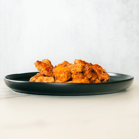 A black plate with golden-brown, crispy Competition Approved Chicken Kebab 1lb sits on a light-colored surface against a plain white background.