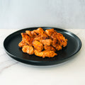 A black plate holds pieces of Competition Approved Chicken Kebab 1lb, expertly cooked and seasoned, set on a white marble surface with a light gray background.