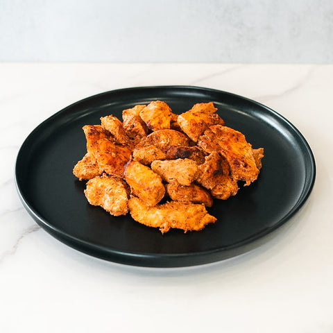 A black plate holds a serving of golden-brown Competition Approved Chicken Kebab 1lb, perfect for meal prep, displayed on a white marble surface with a light gray background.