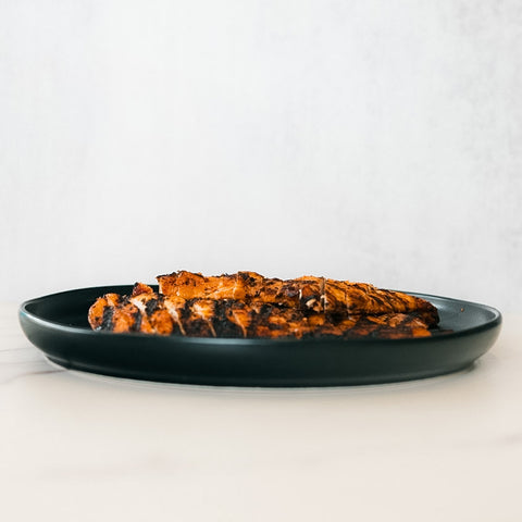 Chipotle Chicken 1lb Competition Approved, sliced and grilled with char marks, is served on a dark plate over a light background—ideal for a healthy dinner or meal prep.