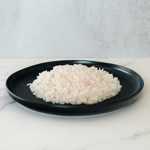 A serving of Competition Approved White Basmati Rice 1lb is arranged on a black plate atop a light surface—an excellent, healthy carb source for meal prep.