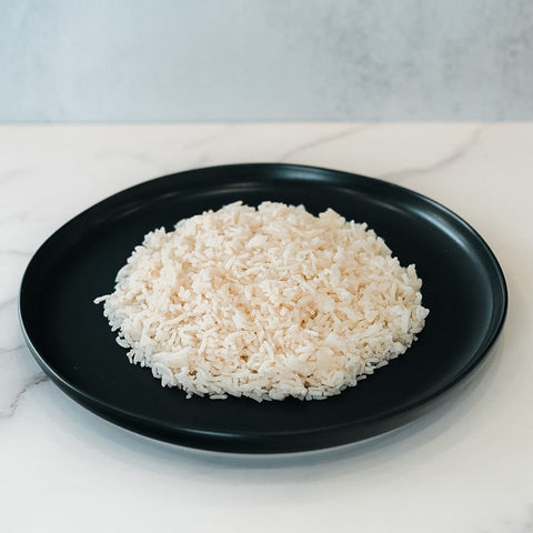 A black plate with fluffy Competition Approved White Basmati Rice 1lb sits on a marble surface, making it the ideal healthy carb choice for meal prep.