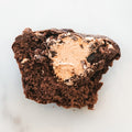 A partially eaten Buffin Muffin - TwistBar with chocolate caramel frosting and creamy chocolate filling, displayed on a light background.