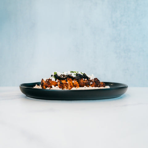 An Olympian Chicken Gyro Bowl - Exclusive featuring a bowl of rice topped with sliced chicken, crumbled cheese, and black olives.