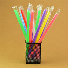 A black mesh pen holder contains several colorful individually wrapped straws from a 24-pack, standing upright against a plain tan background.