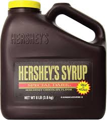 A large 8-pound jug of Dark Chocolate Syrup- For Shakes in a brown handled container with a yellow, white, and red label that reads “Semi-Sweet Chocolate Flavor.”.