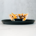 Baja Chicken Tacos feature grilled chicken, shredded cheese, and white sauce in low-carb tortillas, served upright on a black plate—a delicious high-protein meal prep option against a minimalist background.