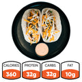 A black plate holds two Baja Chicken Tacos—shredded cheese and greens on low-carb tortillas with a dipping sauce. Nutrition: 360 calories, 32g protein, 32g carbs, 10g fat. Baja Chicken Tacos are ideal for high-protein meal prep.