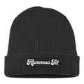 The Hummus Fit Vintage Patch Beanie is a black rib-knit cuffed beanie with a folded brim and a front patch displaying "Hummus Fit" in white cursive lettering.