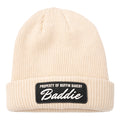 The Buffin Bakery “Baddie” Script Beanie features a cream rib-knit, cuffed design with a black patch reading PROPERTY OF BUFFIN BAKERY Baddie—ideal for cold-weather training or adding athleisure style.