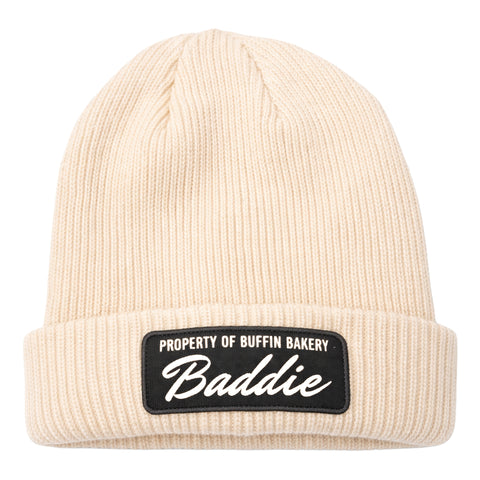 The Buffin Bakery “Baddie” Script Beanie features a cream rib-knit, cuffed design with a black patch reading PROPERTY OF BUFFIN BAKERY Baddie—ideal for cold-weather training or adding athleisure style.