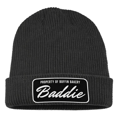 The Buffin Bakery “Baddie” Script Beanie black patch is a black rib-knit cuffed beanie with a folded brim and a rectangular patch—ideal for athleisure outfits or staying warm during cold-weather workouts.