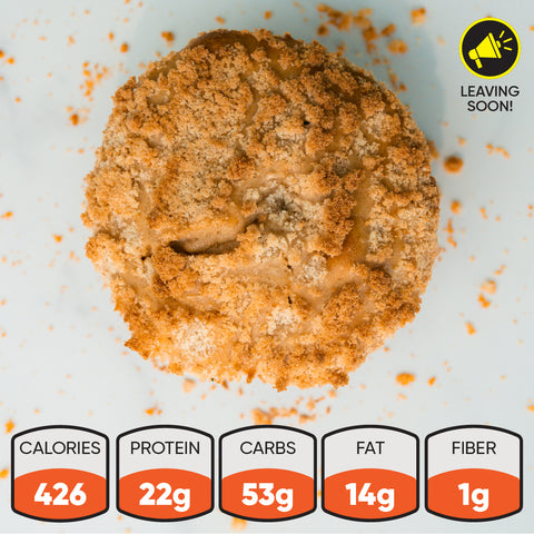 A crumb-topped Buffin Muffin sits on a white surface—ideal for snacking. With 426 calories, 22g protein, 53g carbs, 14g fat, and 1g fiber. A yellow Leaving Soon label shows in the top right corner. Try our variety of flavors.