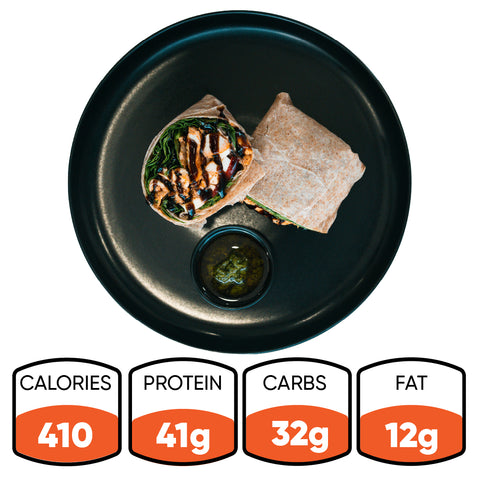 The Grilled Chicken Pesto Wrap, served on a black plate, offers 410 calories, 41g protein, 32g carbs, and 12g fat—ideal for meal preppers wanting a tasty and nutritious boost.