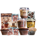 A variety of protein-packed snacks from the Chocolate Lovers Bundle—including cereal bars, protein chocolate puddings, cupcakes, truffles, overnight oats, and packaged desserts—displayed against a white background.