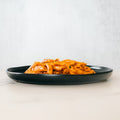 The Clean Bulk Pasta Bowl features penne pasta in rich red tomato sauce on a black plate, served on a light surface—ideal for healthy pasta lovers and perfect for high-protein meal prep.