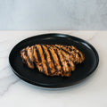 Competition Approved Grilled Chicken 1lb, featuring sliced halal grilled chicken breast with char marks, arranged neatly on a black plate atop a white marble surface—ideal for meal prep.