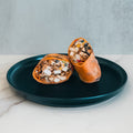 Two halves of the Hey Arnold Burrito—packed with chopped chicken, black beans, corn, and veggies—rest on a dark blue plate against a light backdrop. This high-protein meal is ideal for meal prep.