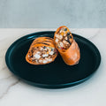 The Hey Arnold Burrito, a grilled high-protein chicken wrap packed with diced chicken, black beans, corn, and veggies, is sliced in half on a dark plate atop light marble with a plain gray backdrop—ideal for meal prep.