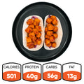 Two soft tacos filled with coated, sauced pieces on a black plate—these Honey Garlic Crispy Chicken Tacos are a delicious option for High-Protein Meal Prep. Nutritional info below: 501 calories, 40g protein, 56g carbs, 13g fat.