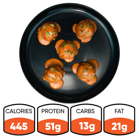 Keto BBQ Chicken Meatballs—five sauced meatballs on a black plate with green onion garnish—offer 445 calories, 51g protein, 13g carbs, and 21g fat, making this high-protein meal a perfect low-carb keto bowl option.