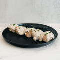 Keto Ricotta Meatballs: Four high-protein, low-carb meatballs topped with creamy white sauce and parsley, served in a row on a black plate. Perfect for those seeking healthy, delicious options.