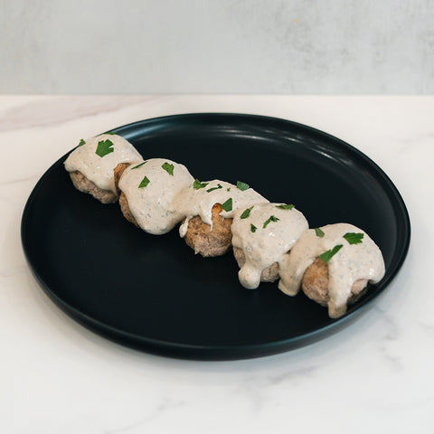 Keto Ricotta Meatballs served on a black plate with creamy white sauce and green herb garnish—an ideal low-carb, high-protein meal option.