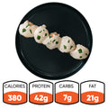 Five Keto Ricotta Meatballs topped with creamy white sauce and herbs are lined up on a black plate. Nutrition facts: 380 calories, 42g protein, 7g carbs, and 21g fat—making this a low-carb, high-protein dish.