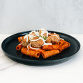 Rigatoni Meatballs: Rigatoni pasta in red sauce topped with three ground-beef meatballs and shredded cheese, served on a sleek black plate—ideal for meal prep or a macro-friendly dinner.