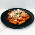 Rigatoni Meatballs: Rigatoni pasta with tomato sauce, four ground-beef meatballs, shredded cheese, and parsley on a black plate—a delicious macro-friendly meal prep option.