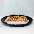 The Southwest Chicken Bowl features sliced grilled chicken with corn salsa over white rice on a black plate—gluten-free and meal-prep friendly. A small dipping sauce dish is in the background.