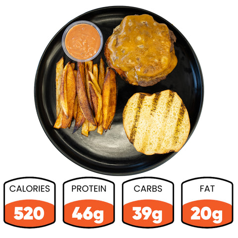 Stacked and Jacked: A high-protein grass-fed beef cheeseburger patty on a grilled bun, with Idaho fries and sauce. 520 calories, 46g protein, 39g carbs, 20g fat. Served on a black plate.
