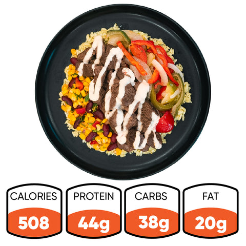 Introducing the Texas Queso Steak Bowl: a hearty, naturally gluten-free meal served on a black plate and loaded with rice, grilled beef, sautéed peppers and onions, corn, beans, and a rich white queso sauce. Each bowl delivers 508 calories with 44g of protein, 38g of carbohydrates, and 20g of fat.